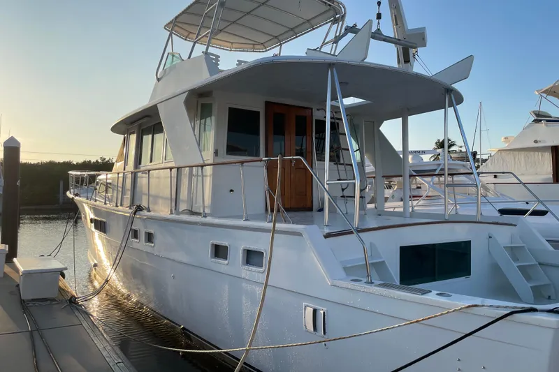 Slide: The Image of 1973 Hatteras 58 Yacht Fisherman docked at sunset, showcasing elegant design and spacious deck. - 5