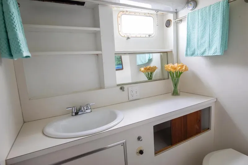 Slide: The Image of 1973 Hatteras 58 Yacht Fisherman bathroom with sink, mirror, and decorative flowers. - 57