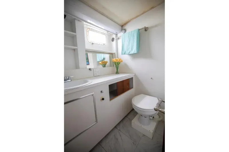 Slide: The Image of Bathroom interior of 1973 Hatteras 58 Yacht Fisherman, featuring sink, toilet, and window. - 58