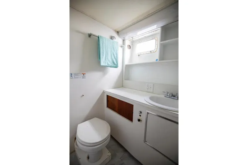 Slide: The Image of 1973 Hatteras 58 Yacht Fisherman bathroom with toilet, sink, and towel rack. - 59