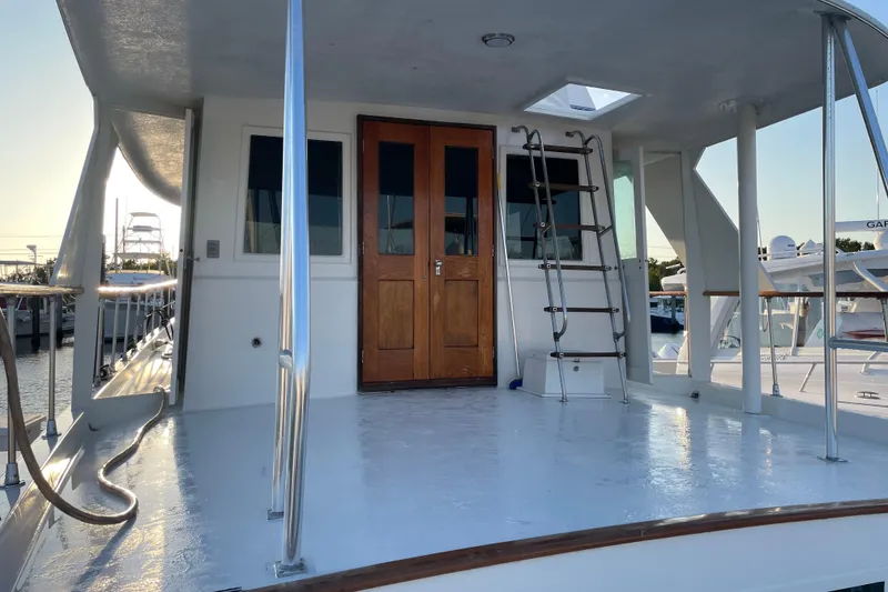 Slide: The Image of 1973 Hatteras 58 Yacht Fisherman deck with wooden doors and ladder, docked at sunset. - 7