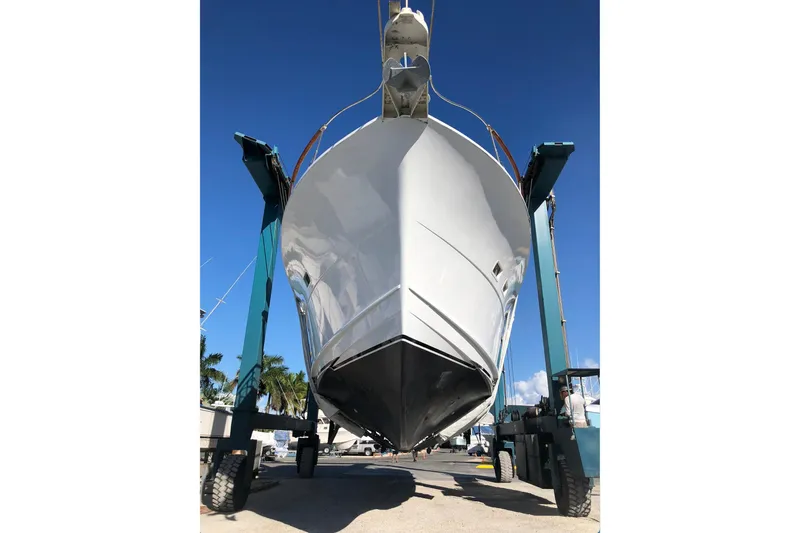 Slide: The Image of 1973 Hatteras 58 Yacht Fisherman lifted by boat hoist under clear blue sky. - 71