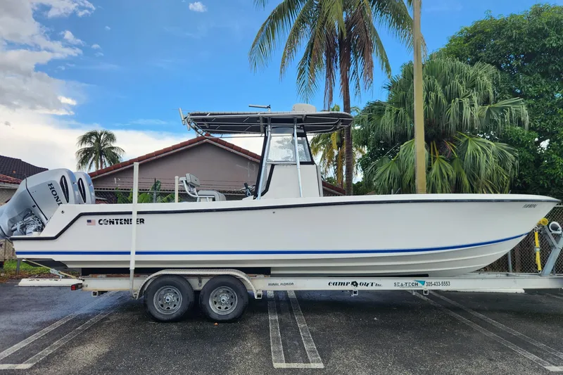 The Image of 2005 Contender 27 Open boat on trailer, parked near palm trees. - 1