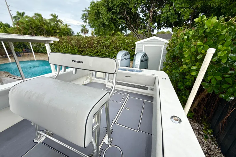 Slide: The Image of 2005 Contender 27 Open boat with Honda engines, near a pool and lush greenery. - 22