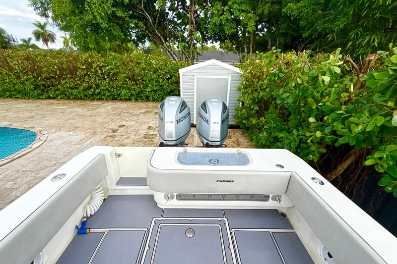 Slide: The Image of 2005 Contender 27 Open boat with dual Honda engines, parked near a pool and greenery. - 7