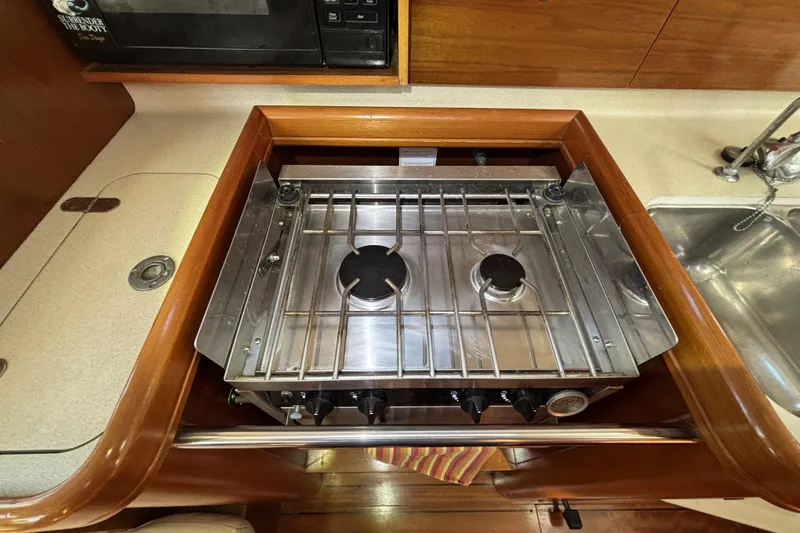 Slide: The Image of Two-burner stove in 1997 Beneteau Oceanis 400 yacht kitchen, with wooden cabinetry and sink. - 68