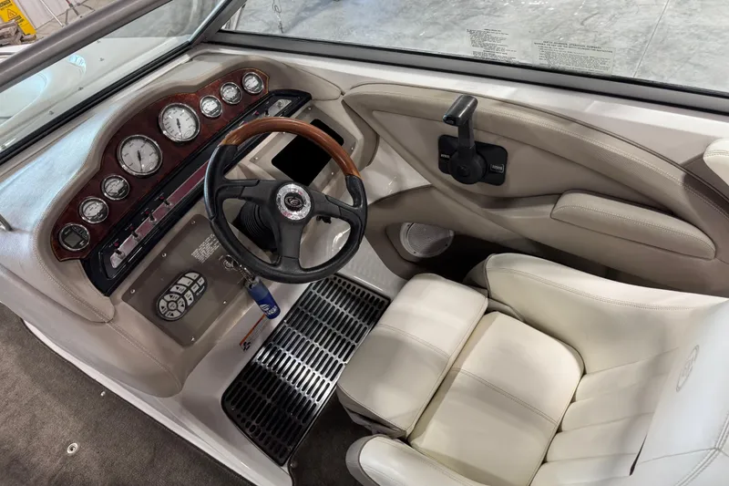Slide: The Image of 2007 Cobalt 232 boat interior with steering wheel, dashboard, and white seating. - 11