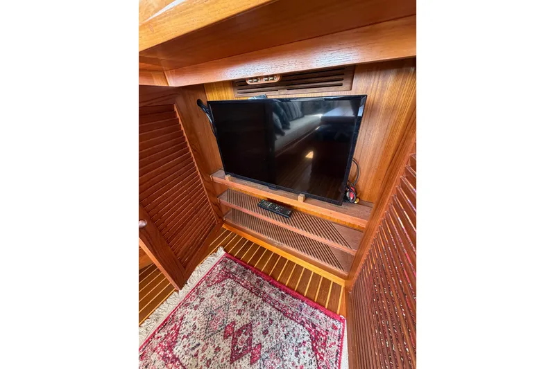 Slide: The Image of Entertainment area with TV in 1988 Offshore Yachts 48 Sedan, featuring wooden interior and rug. - 27