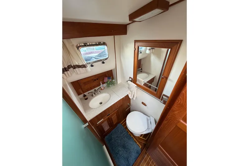 Slide: The Image of 1988 Offshore Yachts 48 Sedan bathroom with wood accents, sink, and mirror. - 61