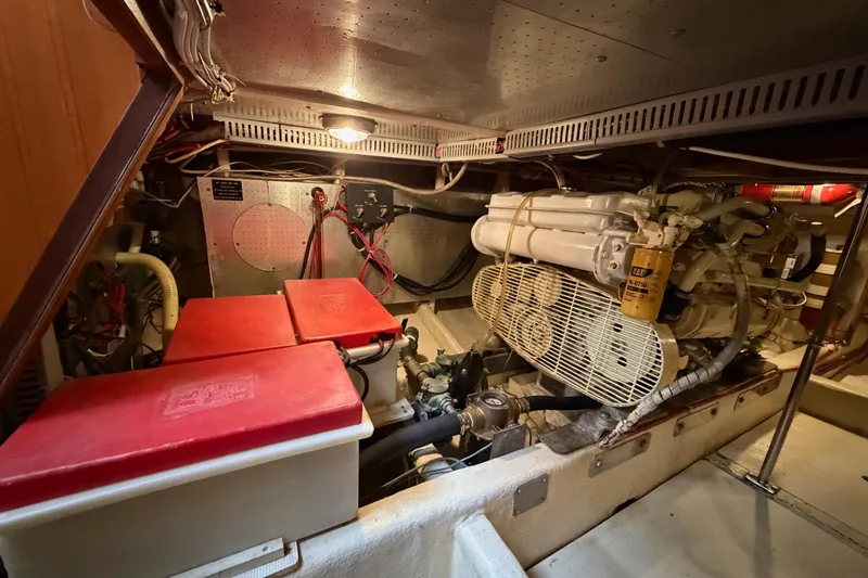 Slide: The Image of Engine room of 1988 Offshore Yachts 48 Sedan, featuring machinery and red battery covers. - 74