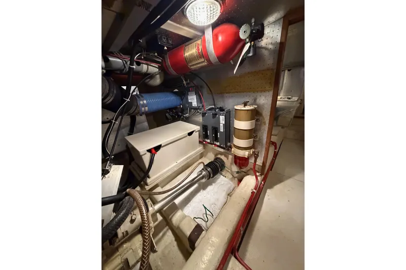 Slide: The Image of Engine room of 1988 Offshore Yachts 48 Sedan with fire extinguisher and mechanical components. - 79