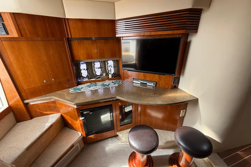 Slide: The Image of Luxurious 2008 Cruisers Yachts 420 Express interior with TV, bar stools, and wooden cabinetry. - 27