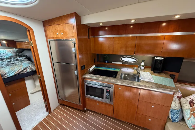 Slide: The Image of 2008 Cruisers Yachts 420 Express interior with kitchen, bed, and wooden cabinetry. - 29