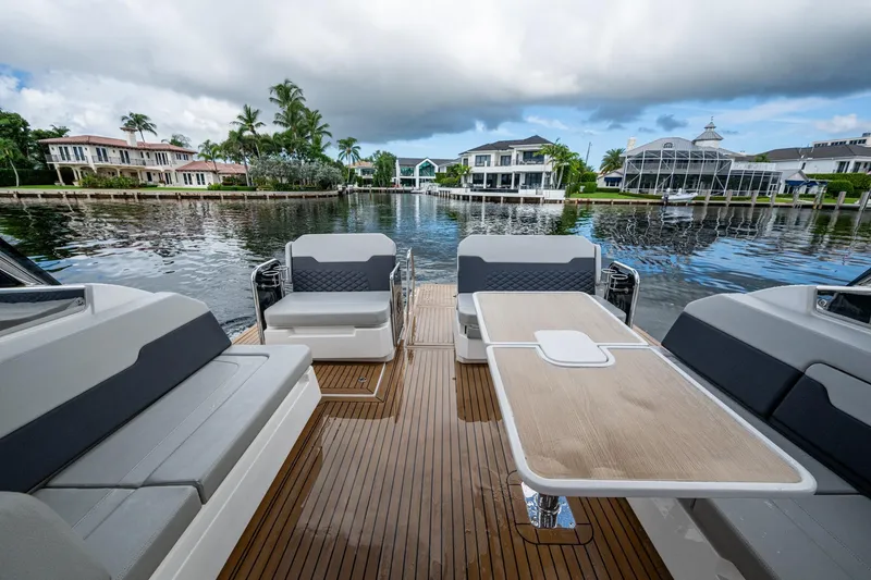 Slide: The Image of 2023 Aquila 32 Power Cat interior with elegant seating and table, overlooking waterfront homes. - 12