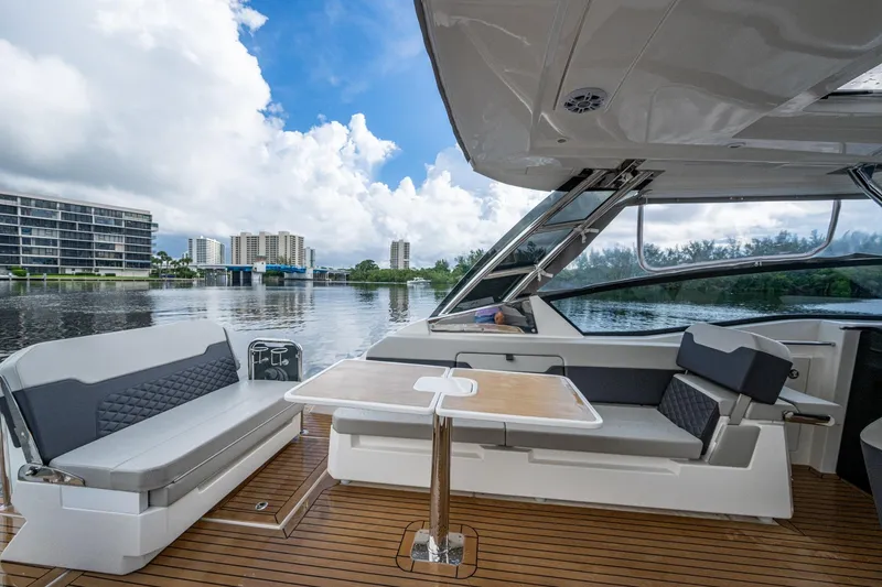 Slide: The Image of 2023 Aquila 32 Power Cat interior with seating and table, overlooking waterfront cityscape. - 15