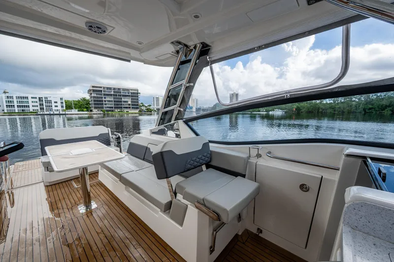 Slide: The Image of 2023 Aquila 32 Power Cat interior with seating and table, overlooking serene waterfront. - 16