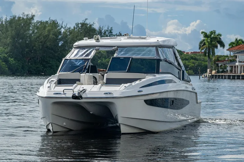Slide: The Image of 2023 Aquila 32 Power Cat cruising on a serene waterway, surrounded by lush greenery. - 37