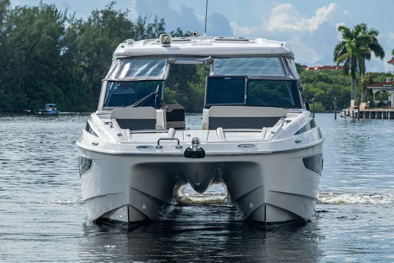Slide: The Image of 2023 Aquila 32 Power Cat cruising on a serene waterway with lush greenery. - 38
