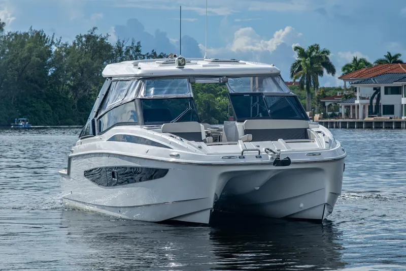 Slide: The Image of 2023 Aquila 32 Power Cat cruising on a serene waterway with lush greenery. - 39