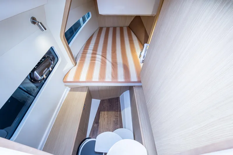 Slide: The Image of 2023 Aquila 32 Power Cat cabin with striped bedding and modern interior design. - 4