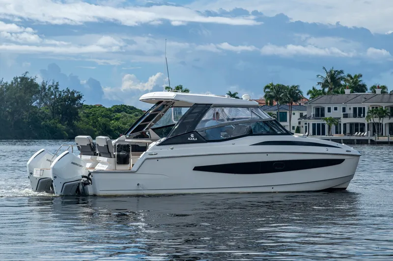 Slide: The Image of 2023 Aquila 32 Power Cat cruising on a scenic waterway with luxury homes in the background. - 44