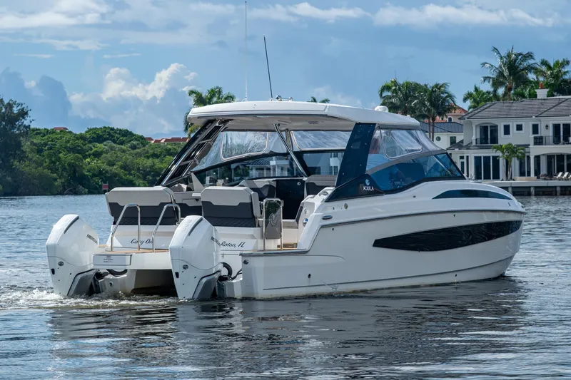 Slide: The Image of 2023 Aquila 32 Power Cat cruising on a scenic waterway near luxury homes. - 45