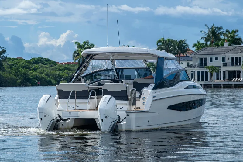 Slide: The Image of 2023 Aquila 32 Power Cat cruising on a scenic waterway near luxury homes. - 46