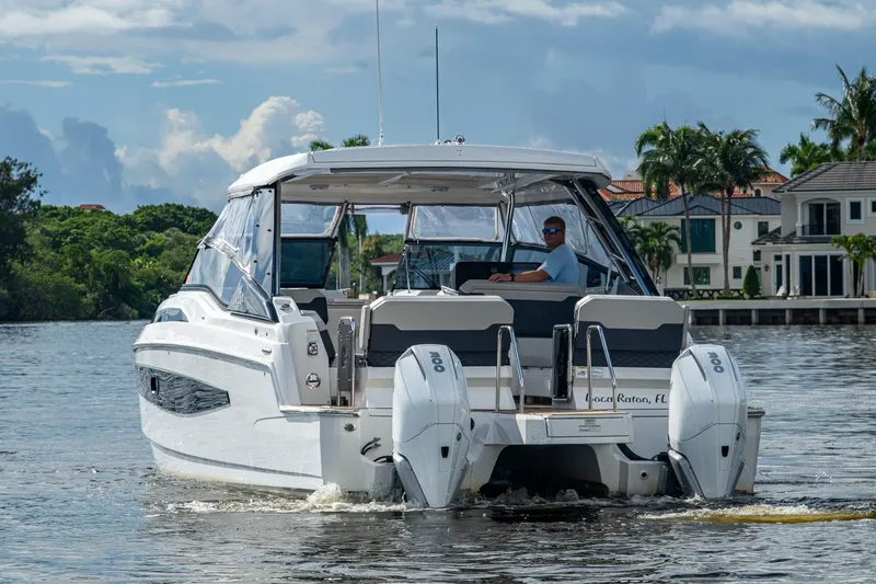 Slide: The Image of 2023 Aquila 32 Power Cat cruising on a scenic waterway with lush greenery. - 48