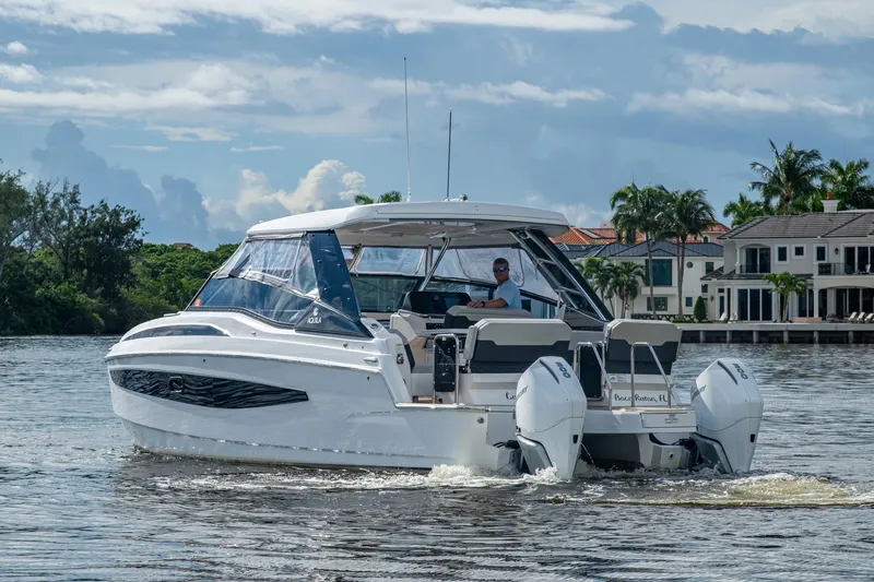 Slide: The Image of 2023 Aquila 32 Power Cat cruising on a scenic waterway with luxury homes in the background. - 49