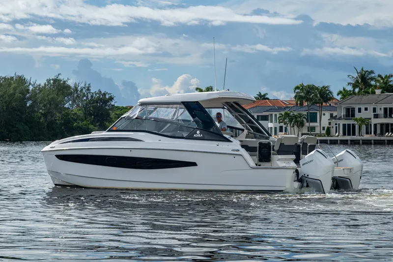 Slide: The Image of 2023 Aquila 32 Power Cat cruising on a scenic waterway with luxury homes in the background. - 50