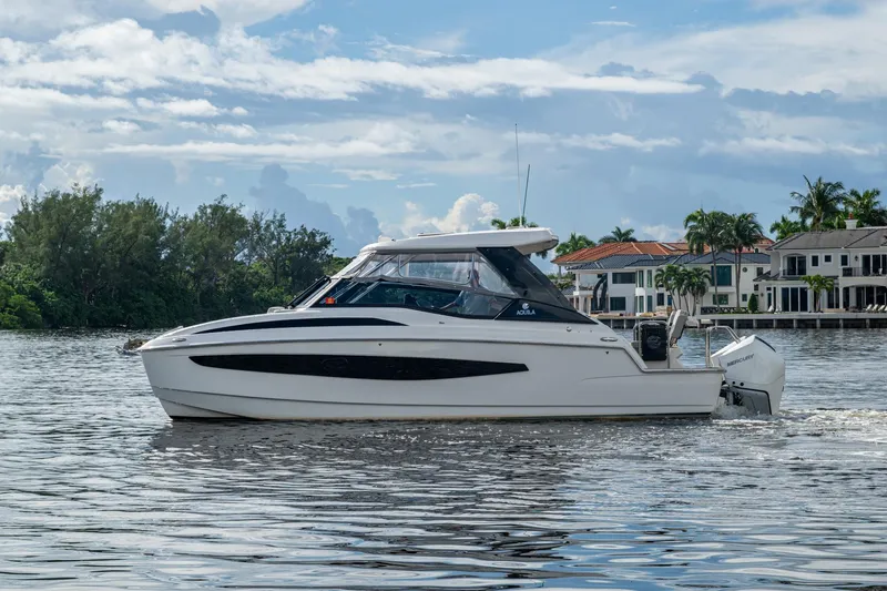 Slide: The Image of 2023 Aquila 32 Power Cat cruising on a scenic waterway with luxury homes in the background. - 51