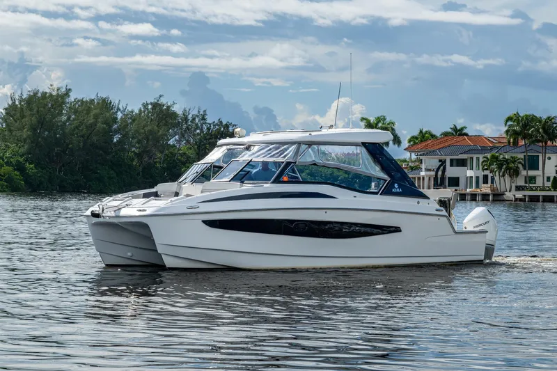 Slide: The Image of 2023 Aquila 32 Power Cat cruising on a serene waterway with lush greenery. - 52
