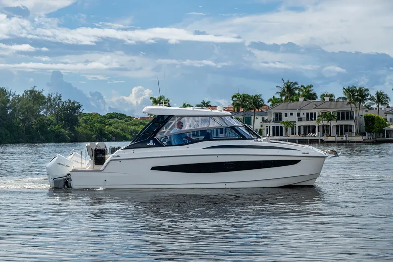 Slide: The Image of 2023 Aquila 32 Power Cat cruising on a scenic waterway with luxury homes in the background. - 54