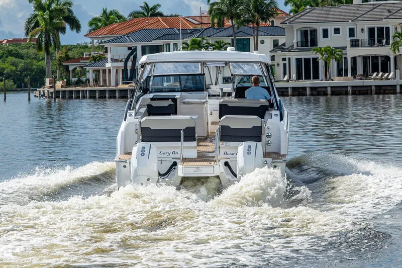 Slide: The Image of 2023 Aquila 32 Power Cat cruising on a scenic waterfront with luxury homes. - 57