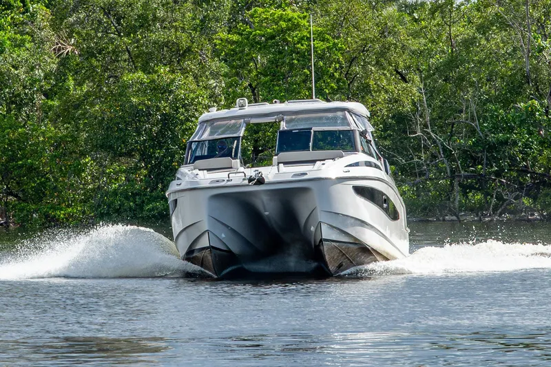 Slide: The Image of 2023 Aquila 32 Power Cat cruising on a serene waterway surrounded by lush greenery. - 60