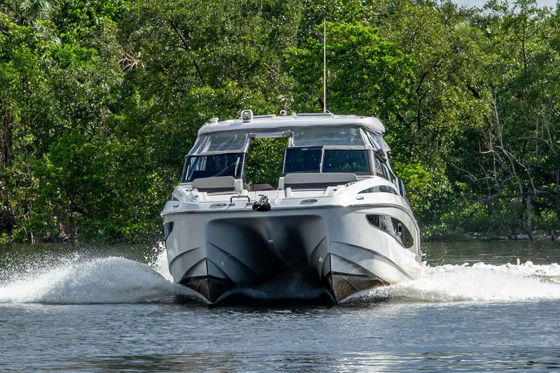 Slide: The Image of 2023 Aquila 32 Power Cat cruising on a river, surrounded by lush greenery. - 61