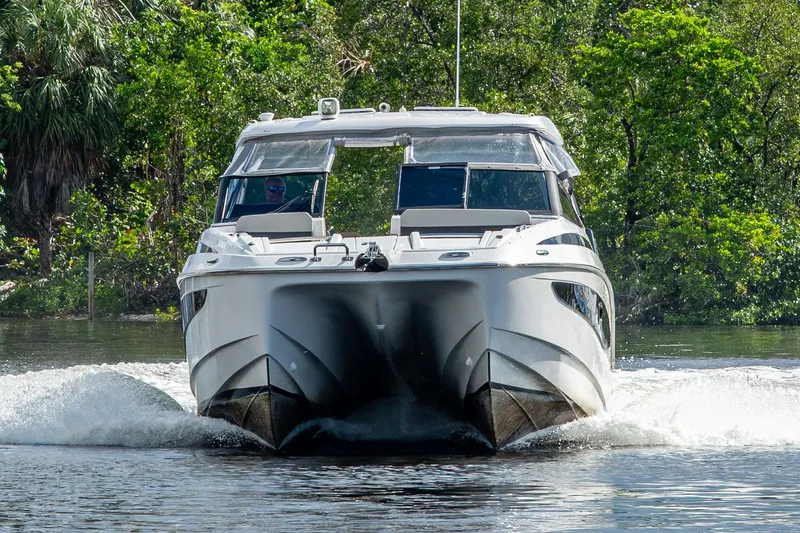 Slide: The Image of 2023 Aquila 32 Power Cat cruising on a scenic waterway surrounded by lush greenery. - 62