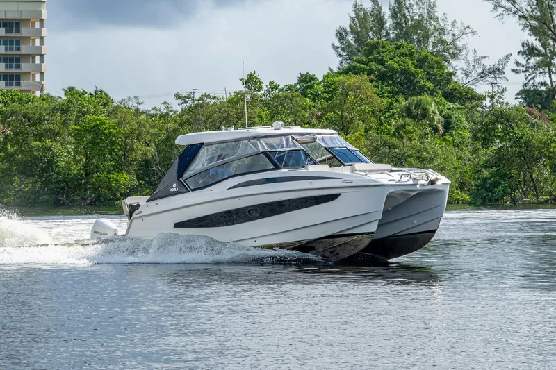 Slide: The Image of 2023 Aquila 32 Power Cat cruising on a scenic waterway with lush greenery. - 64