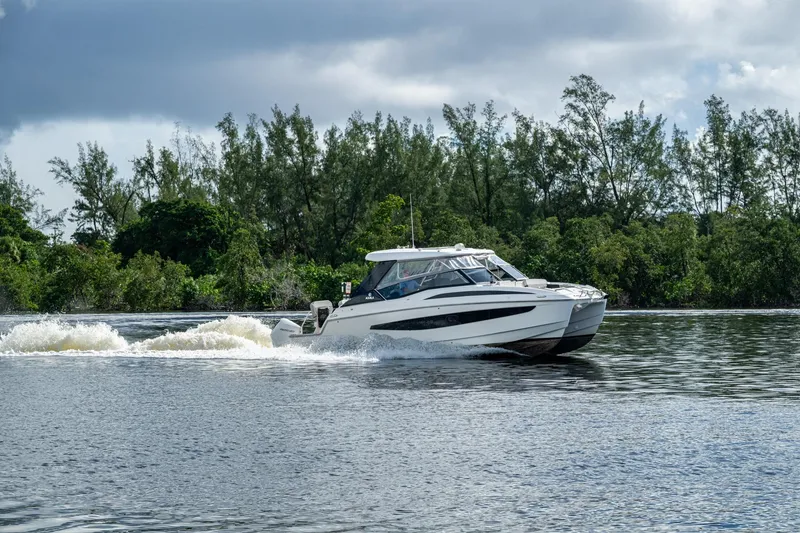 Slide: The Image of 2023 Aquila 32 Power Cat cruising on a serene river with lush greenery. - 66