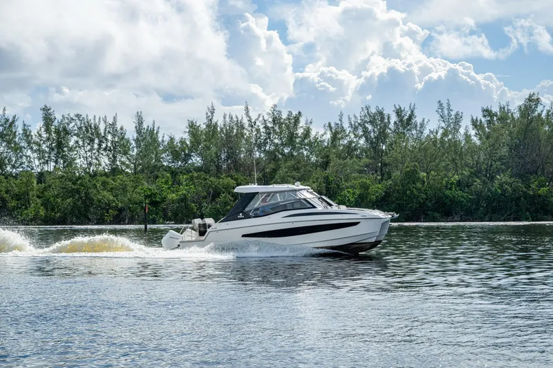 Slide: The Image of 2023 Aquila 32 Power Cat cruising on a serene lake under a cloudy sky. - 67