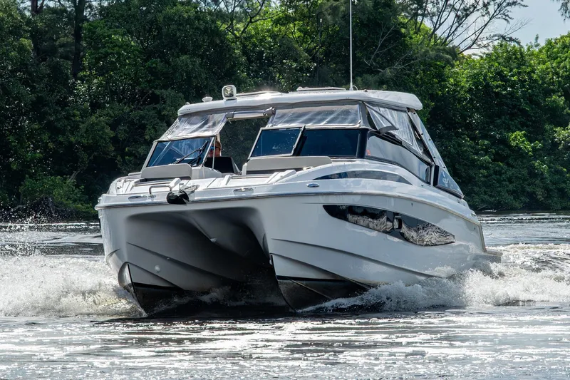 Slide: The Image of 2023 Aquila 32 Power Cat cruising on a scenic waterway surrounded by lush greenery. - 74