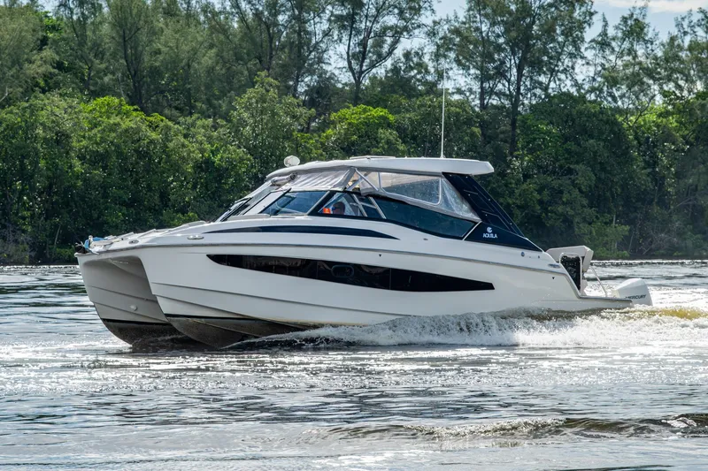 Slide: The Image of 2023 Aquila 32 Power Cat cruising on a scenic waterway with lush greenery. - 75