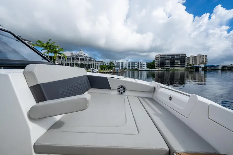 Slide: The Image of 2023 Aquila 32 Power Cat interior with waterfront view, modern seating, and urban backdrop. - 9