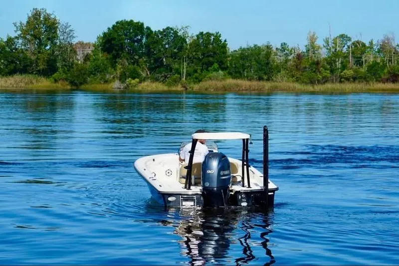 Slide: The Image of 2023 Scout 177 Sport boat cruising on a serene lake with lush green shoreline. - 3
