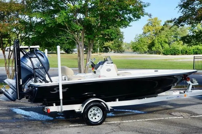 Slide: The Image of 2023 Scout 177 Sport boat on trailer, parked outdoors with trees in background. - 4