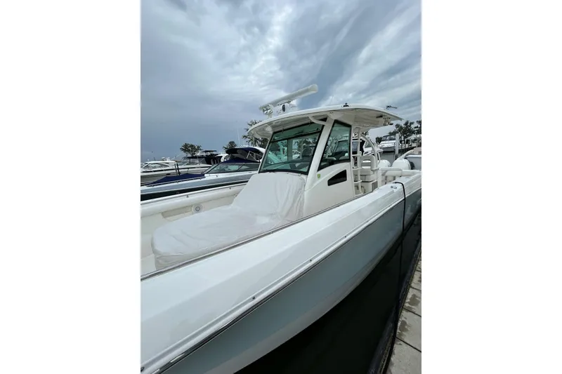 Slide: The Image of 2016 Boston Whaler 370 Outrage boat with white seating, docked among other boats. - 10