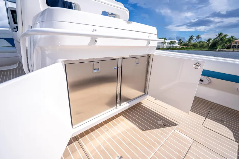 Slide: The Image of 2018 Intrepid 407 boat with open storage compartment, sleek design, and scenic waterfront view. - 22