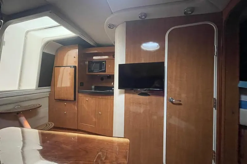 Slide: The Image of 2003 Regal Commodore 3560 IB yacht interior with kitchenette, TV, and wooden cabinetry. - 15