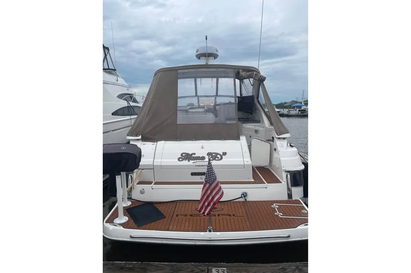 Slide: The Image of 2003 Regal Commodore 3560 IB yacht docked, featuring American flag and covered seating area. - 3