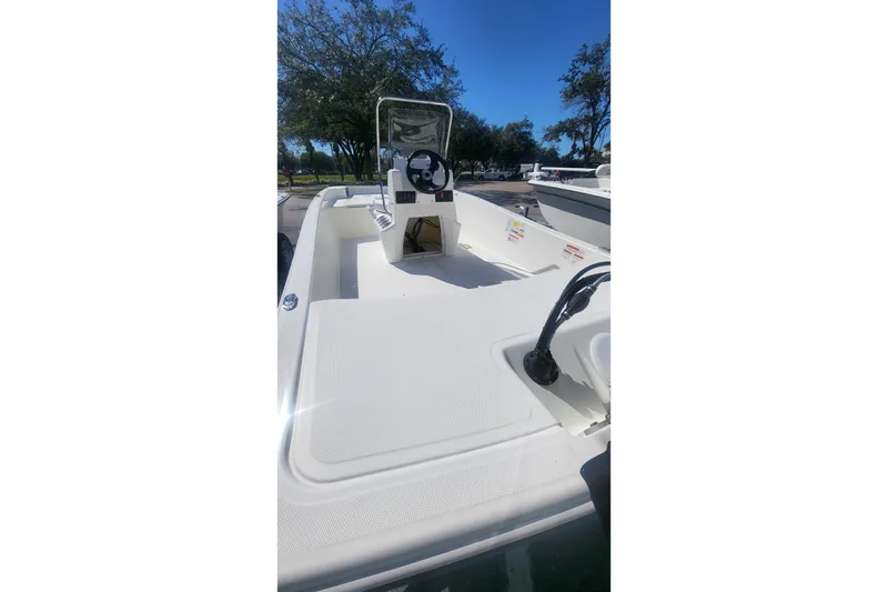 Slide: The Image of 2026 Mako Pro Skiff 17 CC boat interior with steering console, parked outdoors. - 1